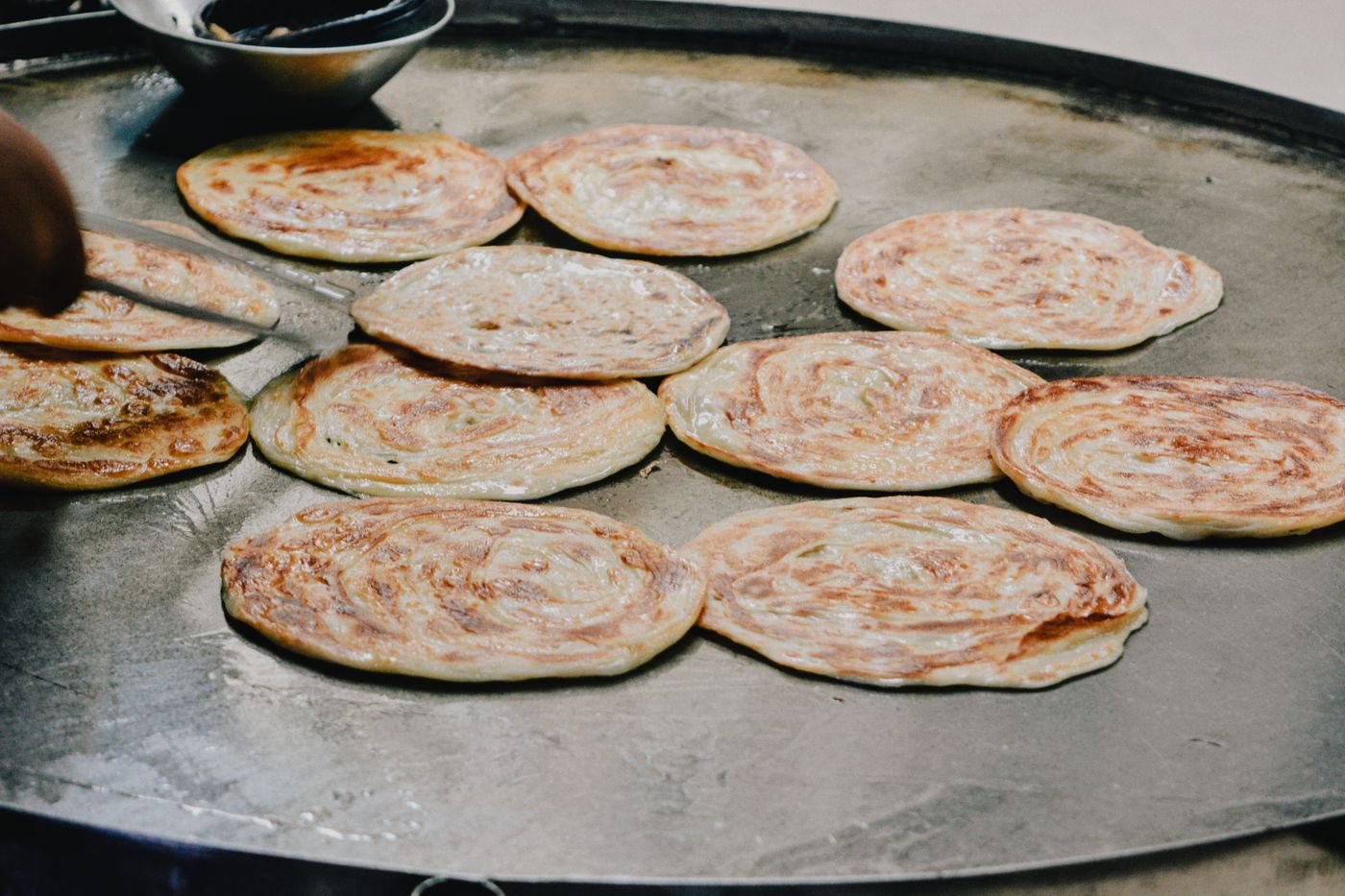 Aloo parathas cooking on a hot griddle