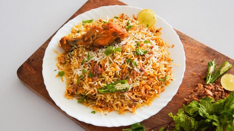Chicken biryani served on a wooden platter with herbs