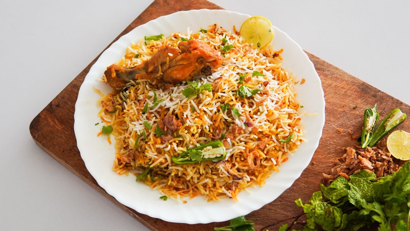 Chicken biryani served on a wooden platter with herbs
