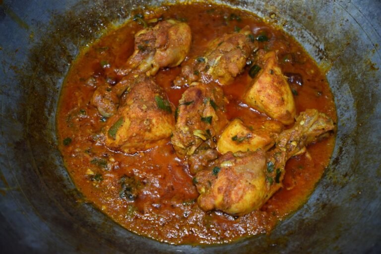 Chicken karahi simmering in a traditional karahi pan with tomatoes and spices