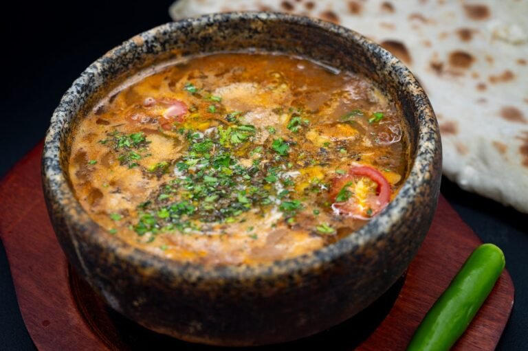 Thick slow-cooked meat stew in a stone bowl with naan